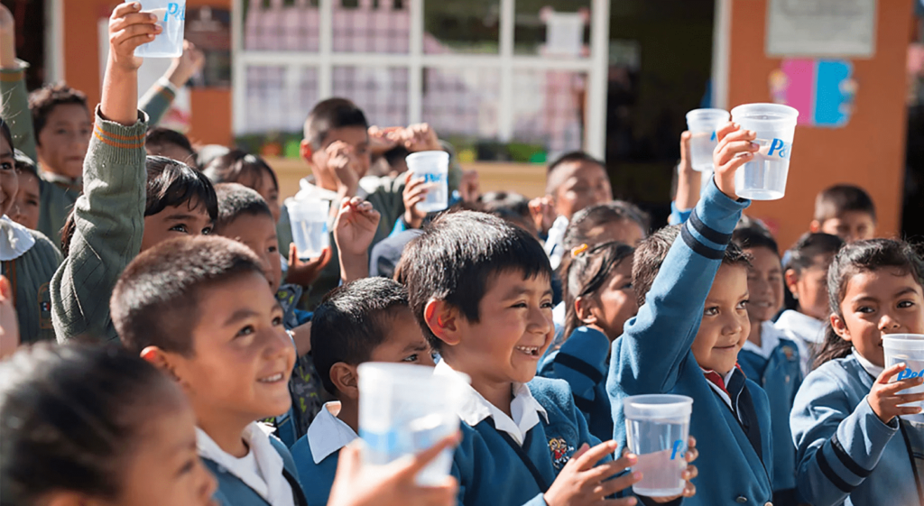School children holding plastic cups filled with water.